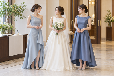 受付前に花嫁とブルー系のドレスを着た友人二人が並ぶ撮影イメージ