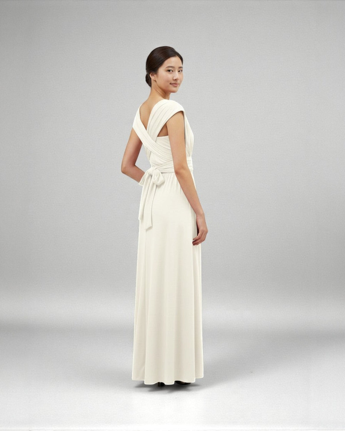 BridesmaidsJP ivory infinity dress with a tie waist, worn by a model with her hair in a bun.