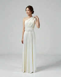 BridesmaidsJP ivory infinity dress styled as a one-shoulder gown on a smiling model against a light grey backdrop.