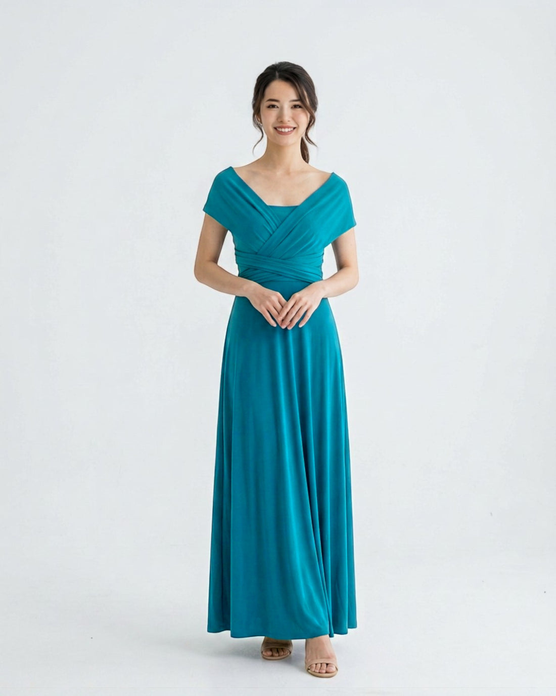 BridesmaidsJP turquoise long infinity dress with a V-neckline and wrap detail, worn by a smiling woman against a white background.