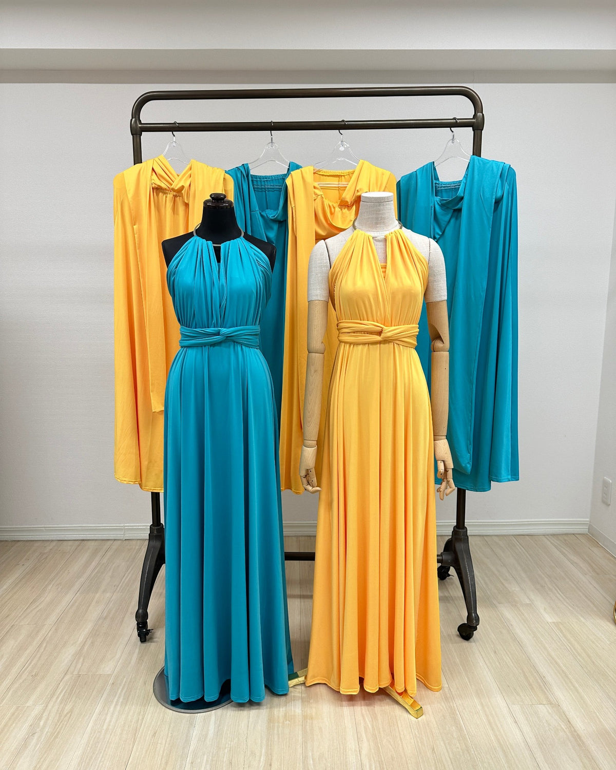 BridesmaidsJP turquoise and orange infinity dresses on mannequins and hangers. Long, flowing, versatile jersey dresses.